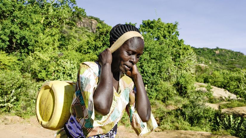 KENIA, ADS Anglican Development Services of Mount Kenya East, Stadt Embu, Dorf Gichunguri, Projekt Regenwasserauffang an einem Felsen und Speicherung in Tanks zur Nutzung in Duerreperioden, Agnes Irima, 44 Jahre, traegt einen gefuellten Wasserkanister nach Hause, ca. 200 Meter