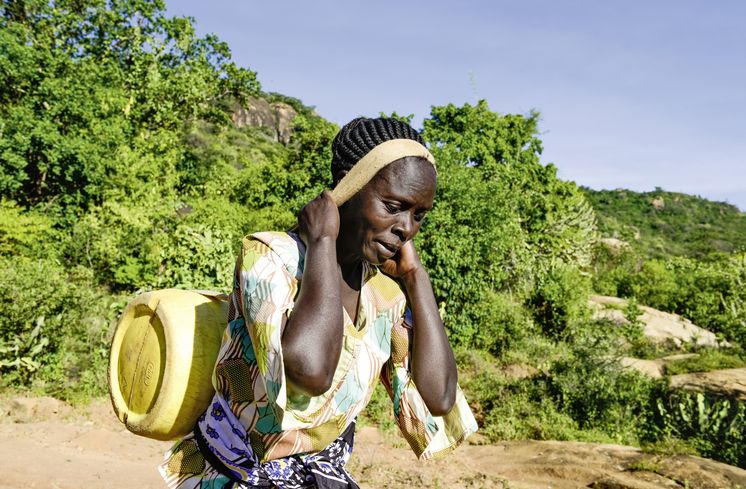 KENIA, ADS Anglican Development Services of Mount Kenya East, Stadt Embu, Dorf Gichunguri, Projekt Regenwasserauffang an einem Felsen und Speicherung in Tanks zur Nutzung in Duerreperioden, Agnes Irima, 44 Jahre, traegt einen gefuellten Wasserkanister nach Hause, ca. 200 Meter