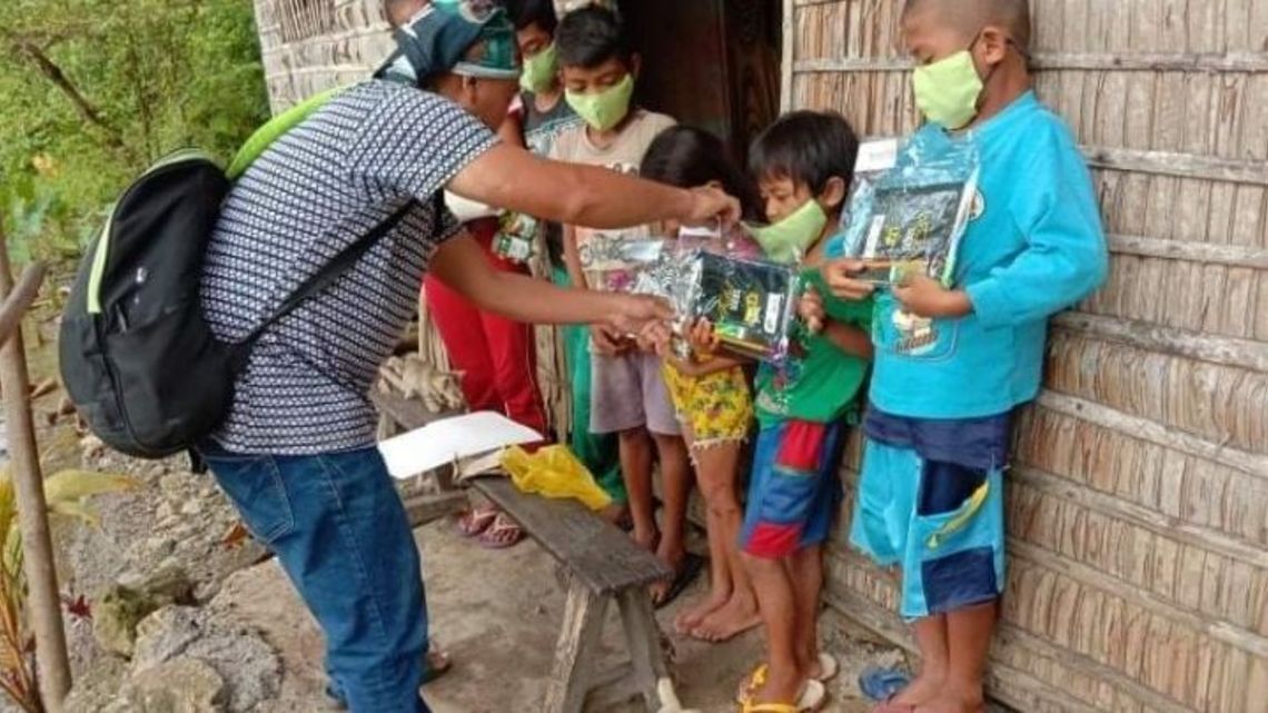Mitarbeiter gibt Schulmaterialien an die Kinder aus