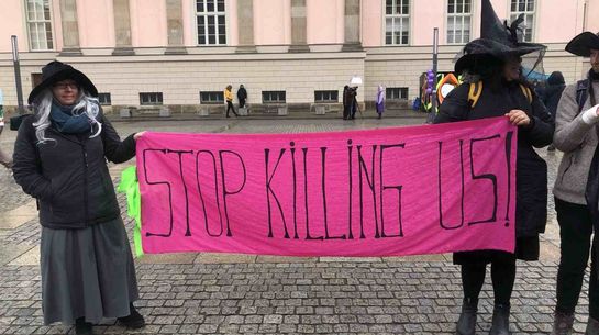 Stop killing us - weltweite Proteste gegen Feminizide Protestierende mit Spruchband stop killing us
