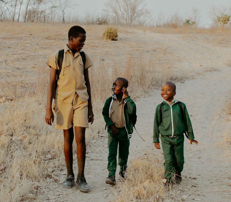 Die Schulkinder Khumbulani Nyati (15), Tawananyasha (7), Lovejoy (6)  auf dem Weg in die Schule. Partnerorganisation: MeDRA