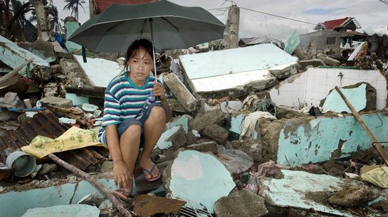 Frau sitzt auf Trümmerhaufen