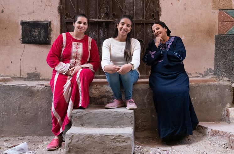 Drei Frauen sitzen an Steinwand