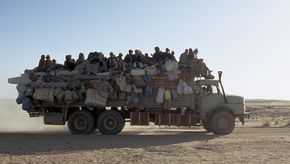 Mit Menschen voll besetzter LKW fährt durch Wüste