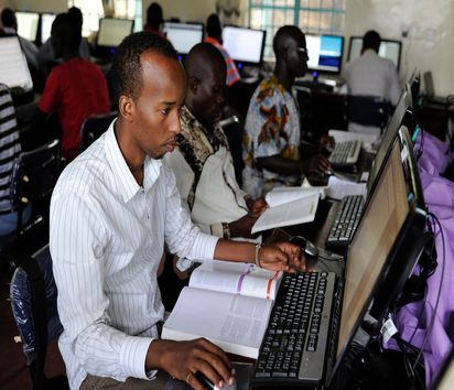 Männer mit Lehrbüchern sitzen vor Computern