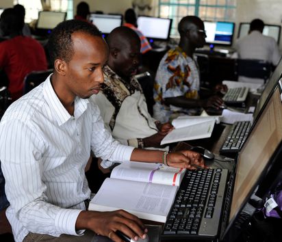 Männer mit Lehrbüchern sitzen vor Computern