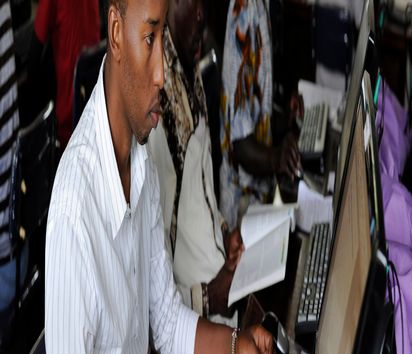 Männer mit Lehrbüchern sitzen vor Computern