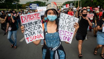 A woman carrying a placard which reads "Duterte Fascist Terrorist Puppet of China" and "Black Lives Matter Resist As One" joins a protest against the Anti-Terrorism Bill on June 4, 2020 at the University of the Philippines in Quezon City, Philippines. Under the proposed bill, a person suspected to be a terrorist can be detained for up to 24 days without a warrant of arrest, be placed under surveillance, and may be sentenced to lifetime imprisonment. The bill has been approved on its third and final reading by the House of Representatives yesterday, June 3. " passes by a police officer during a rally against the Anti-Terrorism Bill on June 4, 2020 at the University of the Philippines in Quezon City, Philippines. Under the proposed bill, a person suspected to be a terrorist can be detained for up to 24 days without a warrant of arrest, be placed under surveillance, and may be sentenced to lifetime imprisonment. The bill has been approved on its third and final reading by the House of Representatives yesterday, June 3.(Photo by Lisa Marie David/NurPhoto/picture alliance