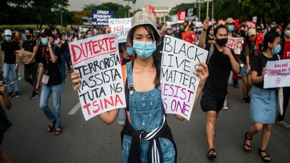 A woman carrying a placard which reads "Duterte Fascist Terrorist Puppet of China" and "Black Lives Matter Resist As One" joins a protest against the Anti-Terrorism Bill on June 4, 2020 at the University of the Philippines in Quezon City, Philippines. Under the proposed bill, a person suspected to be a terrorist can be detained for up to 24 days without a warrant of arrest, be placed under surveillance, and may be sentenced to lifetime imprisonment. The bill has been approved on its third and final reading by the House of Representatives yesterday, June 3. " passes by a police officer during a rally against the Anti-Terrorism Bill on June 4, 2020 at the University of the Philippines in Quezon City, Philippines. Under the proposed bill, a person suspected to be a terrorist can be detained for up to 24 days without a warrant of arrest, be placed under surveillance, and may be sentenced to lifetime imprisonment. The bill has been approved on its third and final reading by the House of Representatives yesterday, June 3.(Photo by Lisa Marie David/NurPhoto/picture alliance