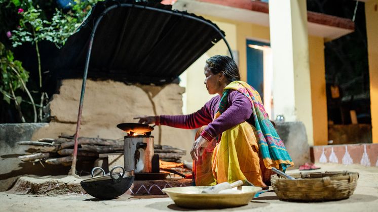 Indische Frau kocht etwas über einem Feuer.