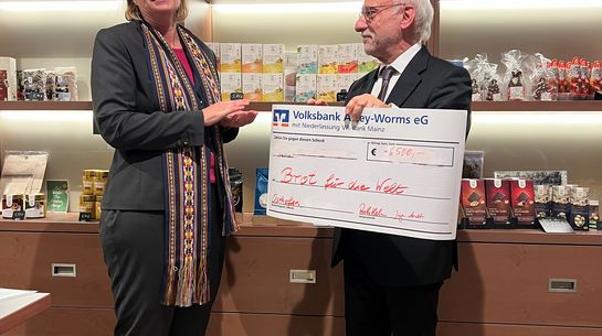 Auf dem Bild sind zwei Personen zu sehen. Die rechts stehende Person hält einen übergroßen Spendenscheck in den Händen, der auf den Betrag von 6.500 Euro aufgestellt ist.