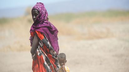 Frau mit kleinem Kind vor Savannenlandschaft
