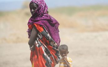 Frau mit kleinem Kind vor Savannenlandschaft