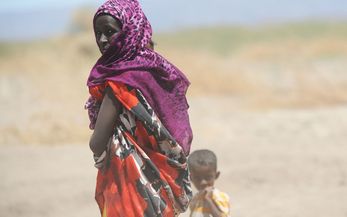 Frau mit kleinem Kind vor Savannenlandschaft