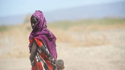 Frau mit kleinem Kind vor Savannenlandschaft