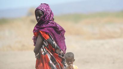 Frau mit kleinem Kind vor Savannenlandschaft
