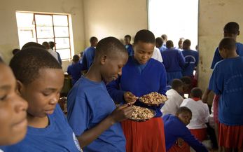 Schülerinnen stehen im Klassenraum und halten Teller mit ihrem Mittagessen
