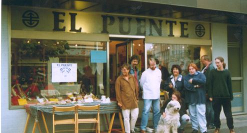 Gruppe von Menschen vor einem Laden mit dem Namen "El Puente"
