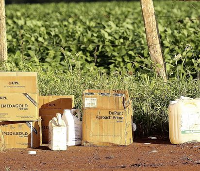 leere Verpackungen und Kanister vor einem grünen Feld.