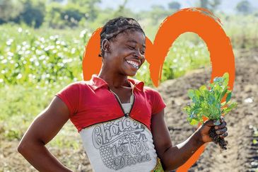 Eine Frau steht auf einem Feld, eingerahmt in ein Herz.