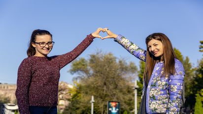 zwei junge Frauen die mit den Händen ein Herz formen