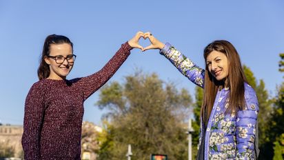 zwei junge Frauen die mit den Händen ein Herz formen