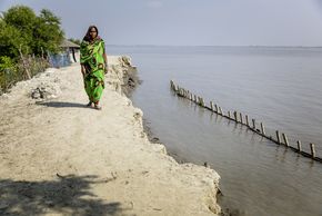 Eine Frau geht über einen Deich in Bangladesch.
