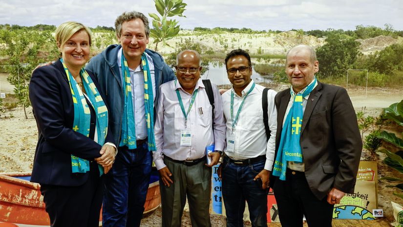 Gruppenfoto vor einem Bild am Messestand von Brot für die Welt