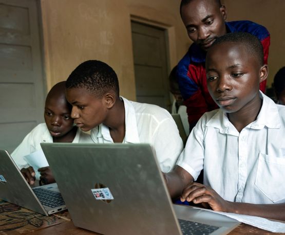 In der Informatik-Klasse übt die Schülerin Bien Aimé Ambire Namegabe (Vordere Reihe, 1. Person v. rechts, 14 Jahre) ihre ersten Schritte am Laptop. Bei Fragen und mit schnellen Shortcuts zur Seite stehend, der Informatik-Lehrer Kasholya Konkwa (in Hintergrund stehend 34 Jahre).In der Informatik-Klasse teilen sich je zwei Schüler*innen ein Laptop. Im November 22 hat das „Institut Namurhera“ sechs Laptops von der Organisation RIO bekommen. Projektpartner: RIO-Réseau d'Innovation Organisationnelle.
