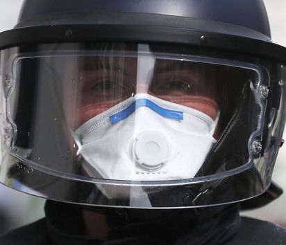 Ein Polizist mit Mundschutz und Einweghandschuhe in Schutzkleidung.