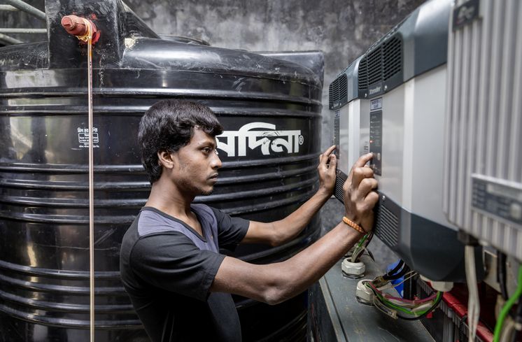 Wasser-Entsalzungsanlage Am Schaltpult Biswajet Biswas, koerperlich beeintraechtigter Operater, bediehnt die CCDB Wasseraufarbeitungsanlage von Vamia, wo Frauen aus der Umgebung ihre Wasserkruege mit sauberem Trinkwasser fuellen koennen. Die Menschen in den kleinen Siedlungen an den Fluessen in der Naehe von Shyamnagar in Sued Bangladesch, spuehren deutlich den Klimawandel. Der Meeresspiegel steigt und Daemme werden zerstört. Da durch werden Felder und die wichtigen Suesswasserteiche ueberflutet und versalzen. CCDB Bangladesch arbeitet an Suesswassergewinnungs-Projekten und sorgt dafuer, dass die Menschen nach und nach sauberes Trinkwasser erhalten.