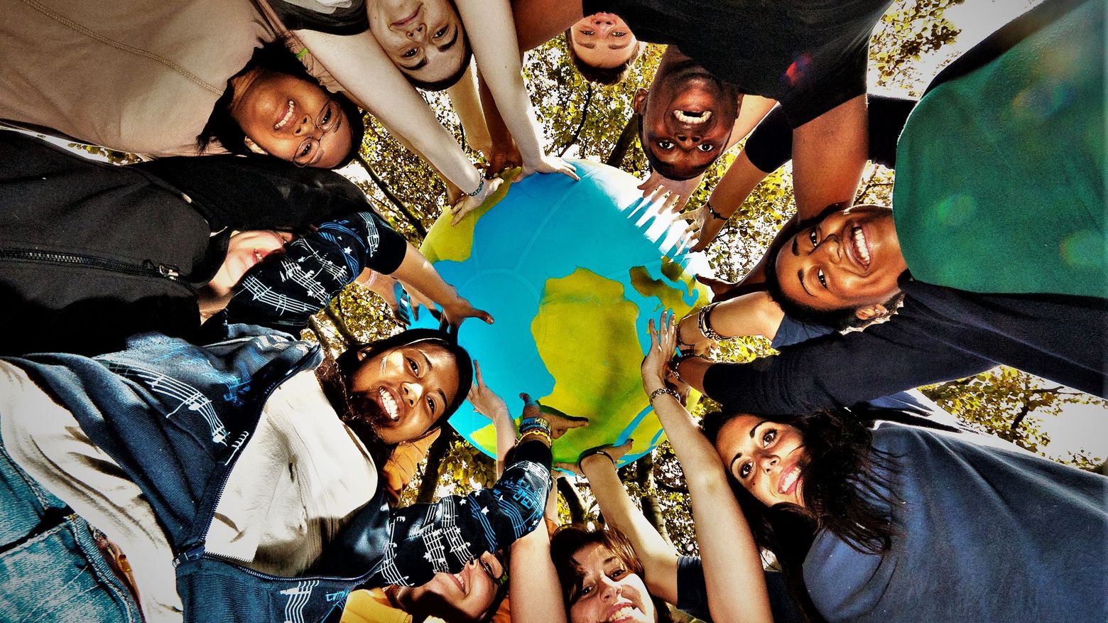 Jugendgruppe hält gemeinsam einen Globus 