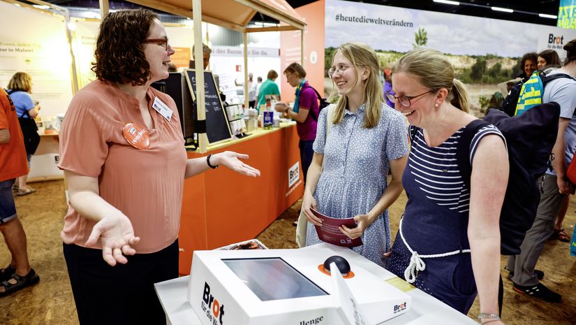 Mitarbeitende mit zwei Messebesucherinnen an der Klima-Challenge