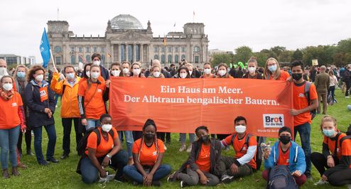 Gruppe von Demonstranten vor dem Reichstag mit Banner mit der Aufschrift "Ein Haus am Meer. Der Albtraum bengalischer Bauern