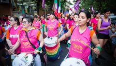 Menschen mit pinken T-Shirts schlagen auf Trommeln auf einer Demonstration.