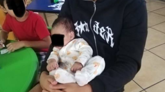 Junger Mann mit Baby auf dem Arm in einer Kindertagesstätte