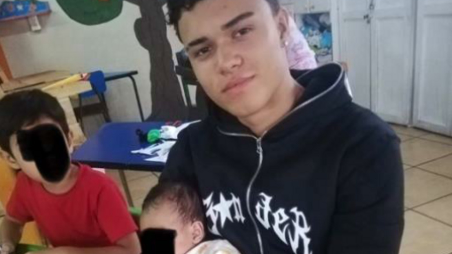 Junger Mann mit Baby auf dem Arm in einer Kindertagesstätte