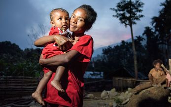 Junge indonesische Mutter hält ihr Kind in den Armen.