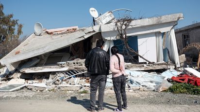 Ehepaar steht vor dem vom Erdbeben zerstörten Haus in Hatay