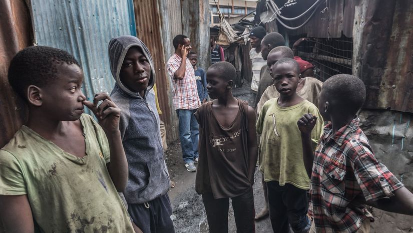 Straßenkinder in zerrissener Kleidung zwischen kaputten Häusern aus Wellblech