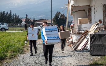 Bilge Menekşe von der Diakonie Katastrophenhilfe und Mitarbeiter von hayata destek tragen Hilfspakete