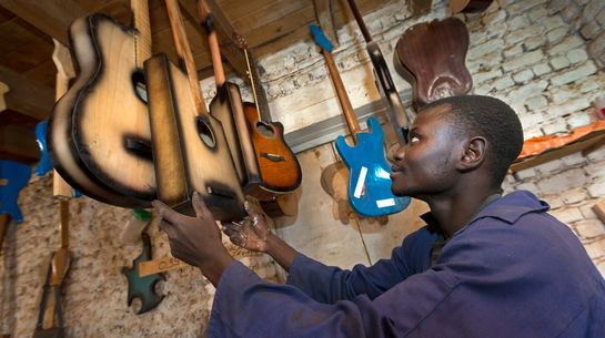 Ehemaliger Kindersoldat in der Demokratischen Republik Kongo in seinem Beruf als Gitarrenbauer