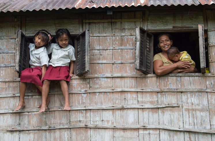 Philippinen / Negros Reyca Jay Occeñola (10, links) und Karylle Occeñola (8) sitzen in den Fenstern ihres Zuhauses und posieren in ihren Schuluniformen. Rechts sieht man ihre Mutter Janet Occeñola mit dem Baby Shynell.Kampf gegen Kinderarbeit: Auf der philippinischen Insel Negros schuften tausende Minderjährige auf Zuckerrohrplantagen und Reisfeldern - oder sie müssen mit dem Brennen von Holzkohle oder dem Verkaufen von Alltagsgegenständen Geld verdienen. Gegen die illegale Ausbeutung engagiert sich die Organisation Quidan Kaisahan. Mit Erfolg: Inzwischen gehen viele Kinder zur Schule. Schulabbrecher erhalten mit Förderunterricht die Chance auf einen Abschluss. Und dank Landwirtschaftsprojekten finden ihre Eltern einen Weg aus der Armut. Philippinen / Insel Negros / Provinz Negros OccidentalFoto: Helge Bendl / Brot für die Welt