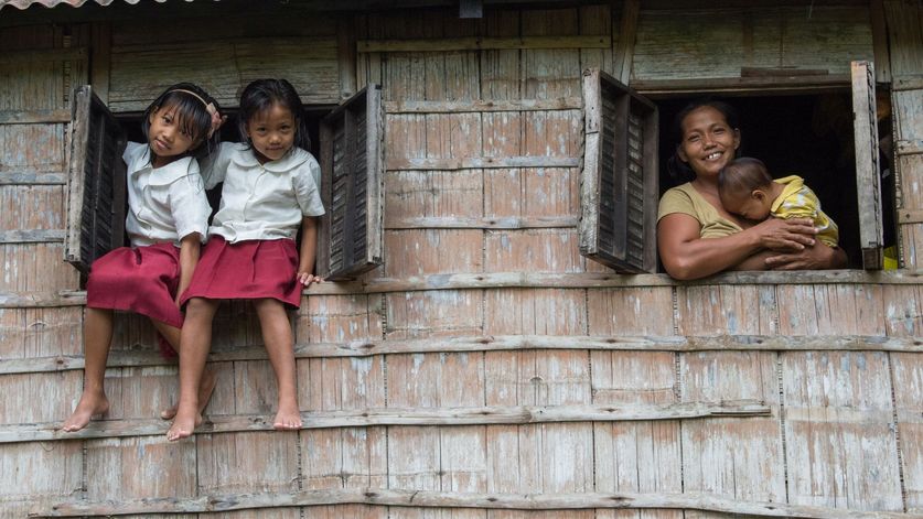 Philippinen / Negros Reyca Jay Occeñola (10, links) und Karylle Occeñola (8) sitzen in den Fenstern ihres Zuhauses und posieren in ihren Schuluniformen. Rechts sieht man ihre Mutter Janet Occeñola mit dem Baby Shynell.Kampf gegen Kinderarbeit: Auf der philippinischen Insel Negros schuften tausende Minderjährige auf Zuckerrohrplantagen und Reisfeldern - oder sie müssen mit dem Brennen von Holzkohle oder dem Verkaufen von Alltagsgegenständen Geld verdienen. Gegen die illegale Ausbeutung engagiert sich die Organisation Quidan Kaisahan. Mit Erfolg: Inzwischen gehen viele Kinder zur Schule. Schulabbrecher erhalten mit Förderunterricht die Chance auf einen Abschluss. Und dank Landwirtschaftsprojekten finden ihre Eltern  einen Weg aus der Armut. Philippinen / Insel Negros / Provinz Negros OccidentalFoto: Helge Bendl / Brot für die Welt