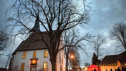 Weihnachtsmarkt an einer Kirsch bei Dämmerung mit Lichterketten beleuchtet