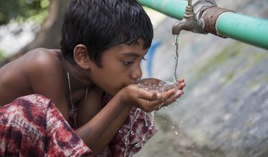 A village boy drinking water from the community based Rain Water Storage Plant of Lighthouse Project at Patharghata in Barguna district, Bangladesh