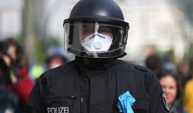 Ein Polizist mit Mundschutz und Einweghandschuhe in Schutzkleidung.