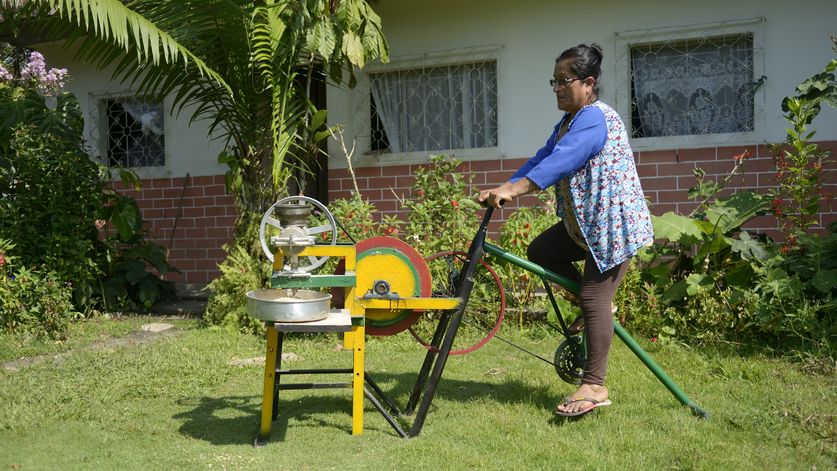 Belia Vaca (53 Jahre) mahlt Mais mit ihrer Fahrradmaschine - Anwesen des Ehepaares Belia Vaca (53 Jahre) und Galo Rodgrigues (63), Ort "Y del Mitad del Mundo", Provinz Sucumbíos, Ecuador; Foto: Florian Kopp / Brot für die Welt