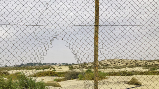 Das Bild zeigt einen Zaun in der Wüste, dem Ort, an dem viele Migrant*innen von tunesischen Sicherheitskräften ausgesetzt werden. 