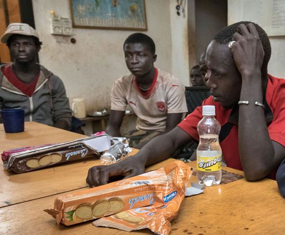 Gruppe von Männern sitzt an einem Tisch, Kekse und Getränke auf dem Tisch